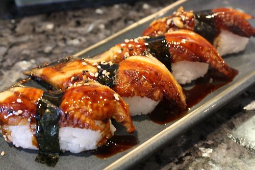 sushi is served on a plate with sauce