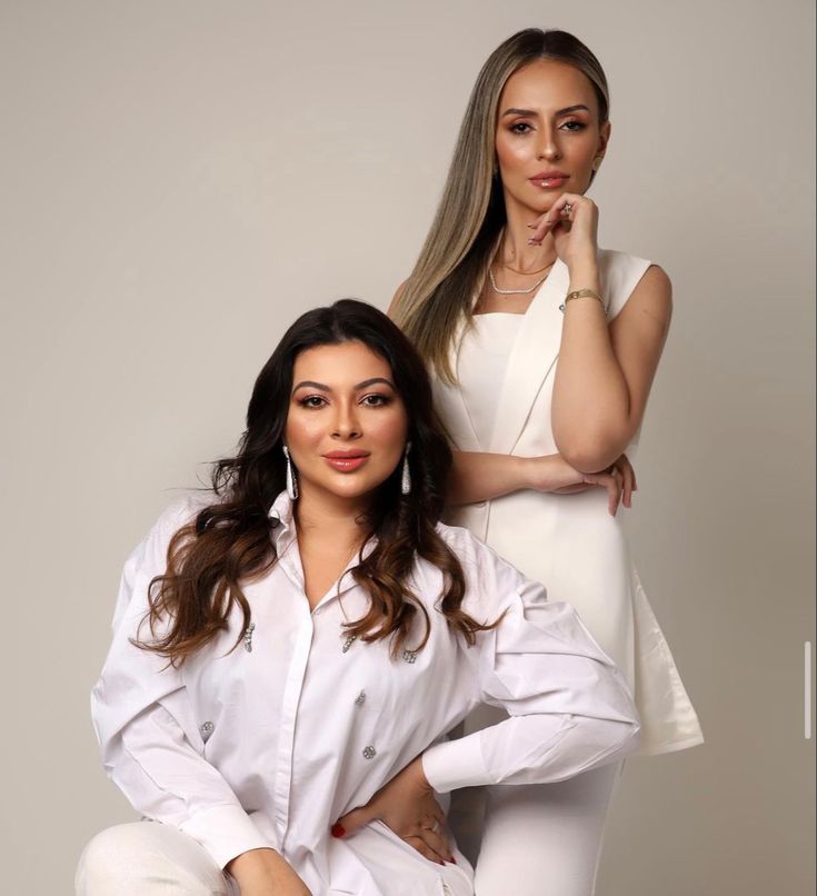 two women are posing for the camera with their hands on their hipss and one is leaning against her head