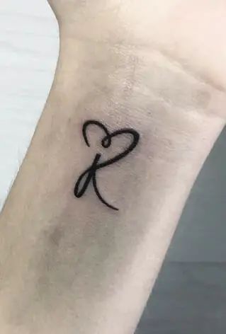 a small black heart tattoo on the ankle