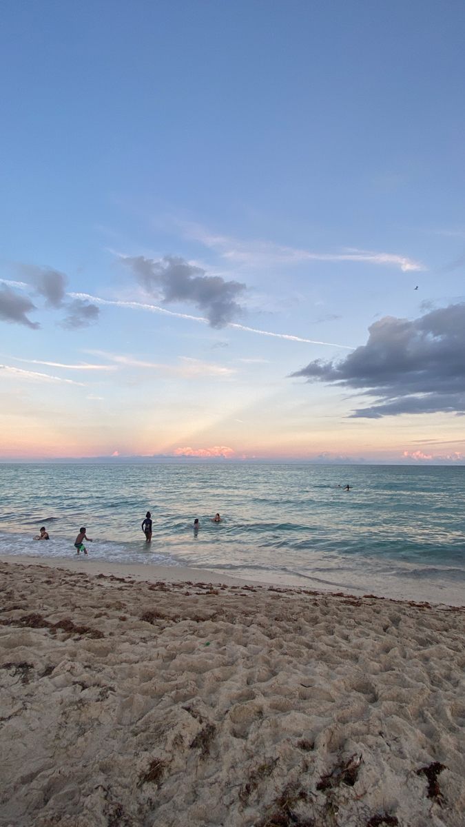 people are on the beach at sunset with surfboards