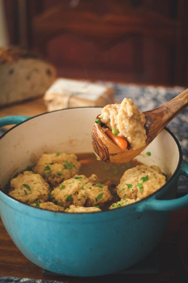 a wooden spoon full of food sitting in a blue pot on top of a table