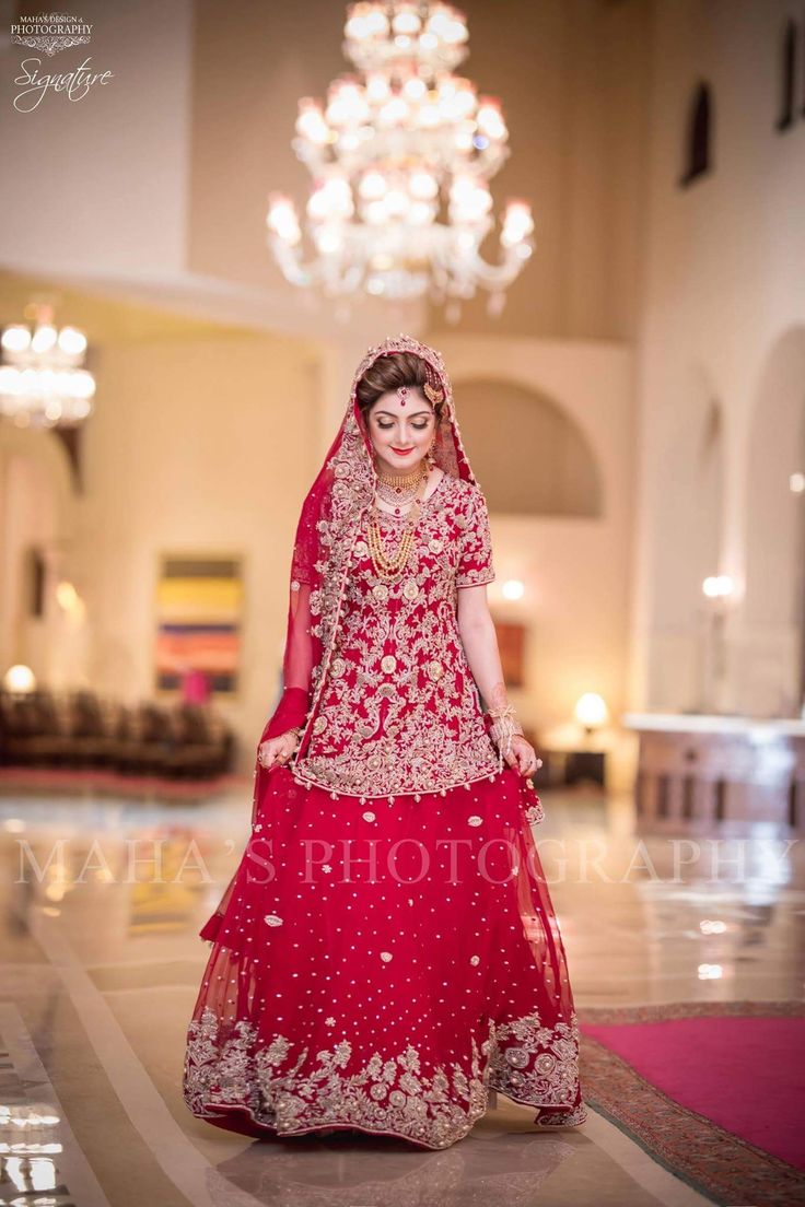 a woman in a red and gold bridal gown with a chandelier hanging from the ceiling