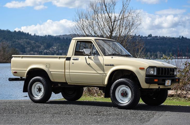 a beige pick up truck parked next to a body of water