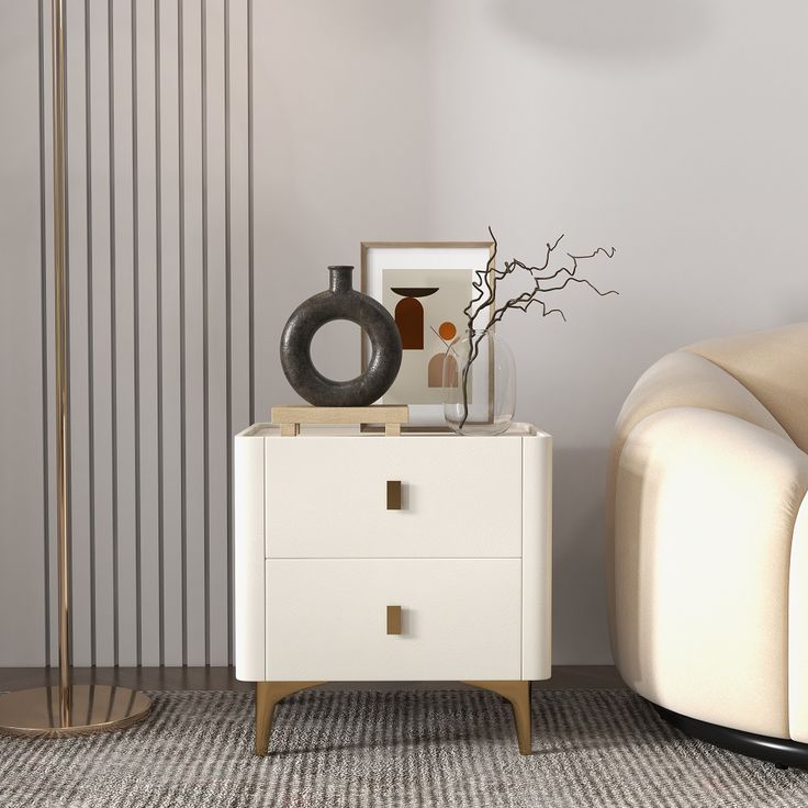 a living room with a white chair and a black vase on top of a cabinet