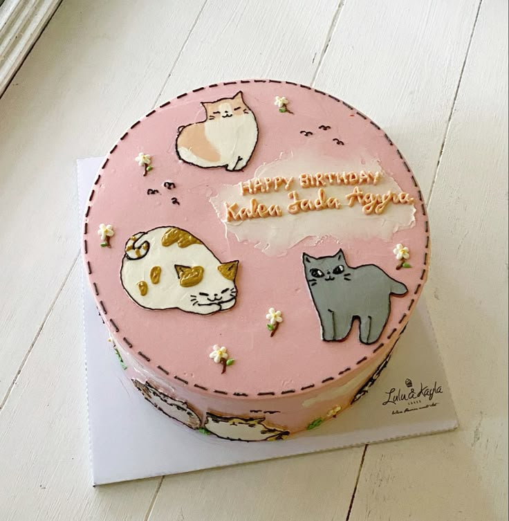 a pink birthday cake with cats on it