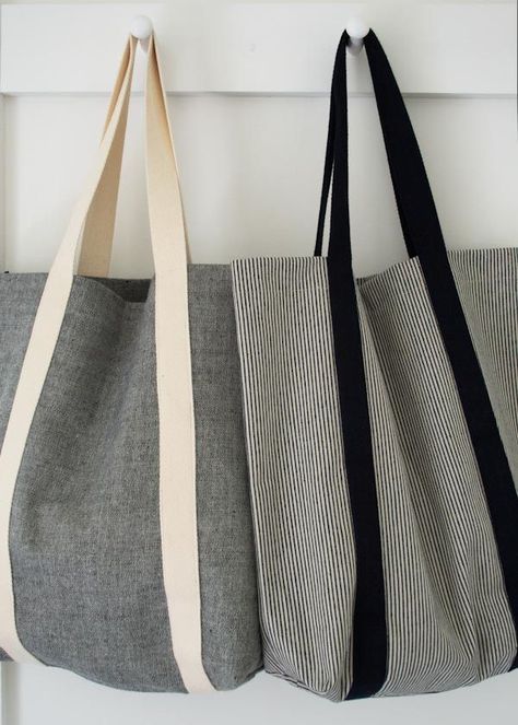 three bags hanging on the wall with one black and white striped tote bag in front