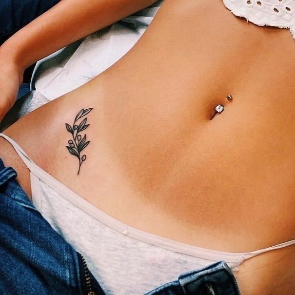 a woman's stomach with a flower tattoo on the side and an ear piercing