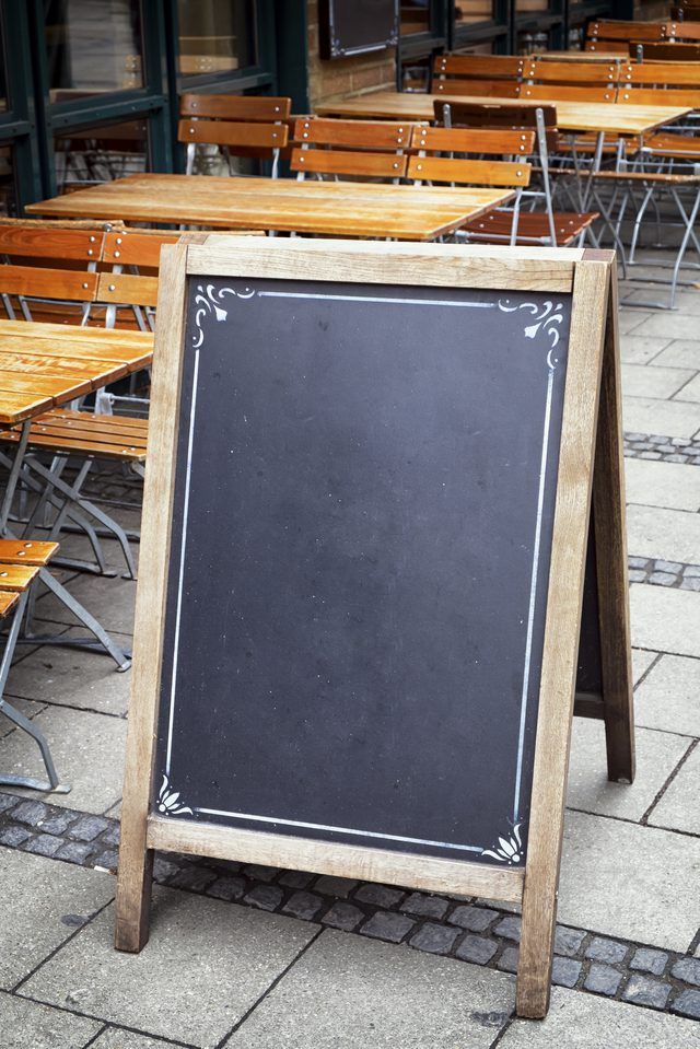 an empty chalkboard sitting in front of wooden tables