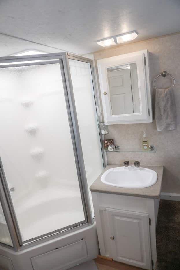 a bathroom with a sink, mirror and shower stall in it's corner area