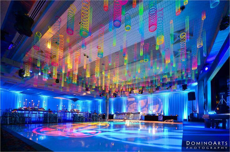 an indoor dance floor is lit up with colorful lights