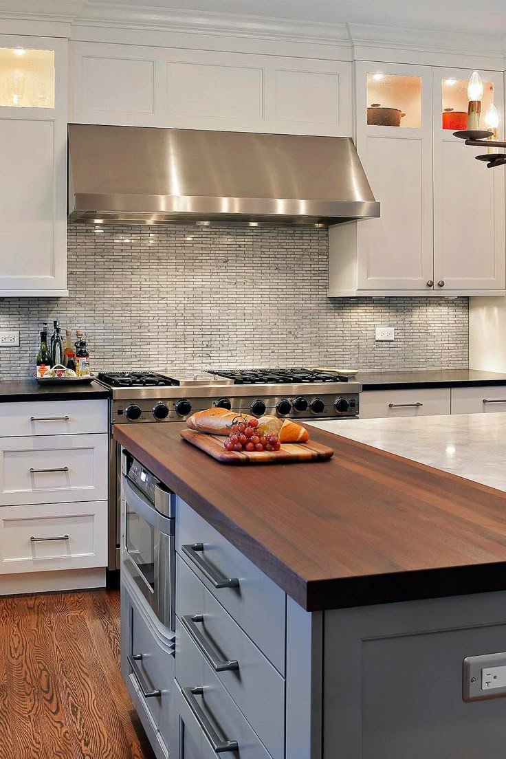 a kitchen with white cabinets and wood counter tops, stainless steel appliances and an island in the middle