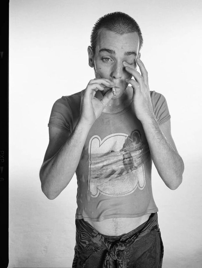 a black and white photo of a man holding his hands to his face while looking at the camera