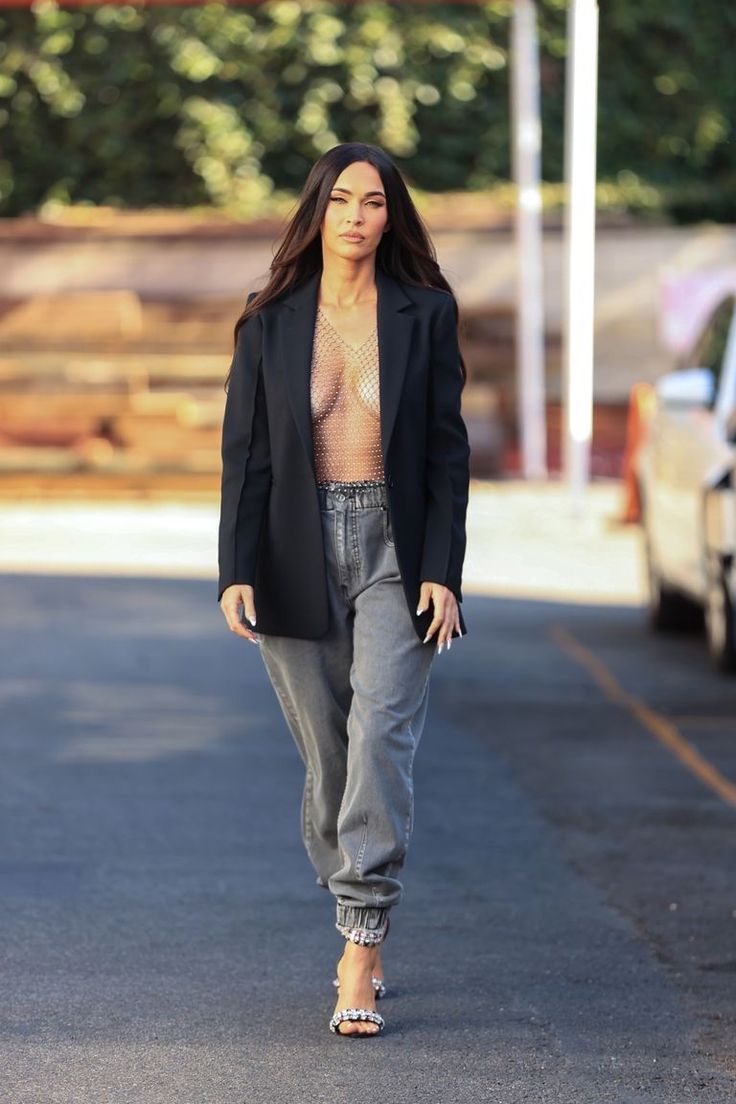 a woman walking down the street wearing jeans and a blazer