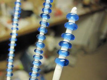 two toothbrushes with blue and white beads hanging from the top of each one