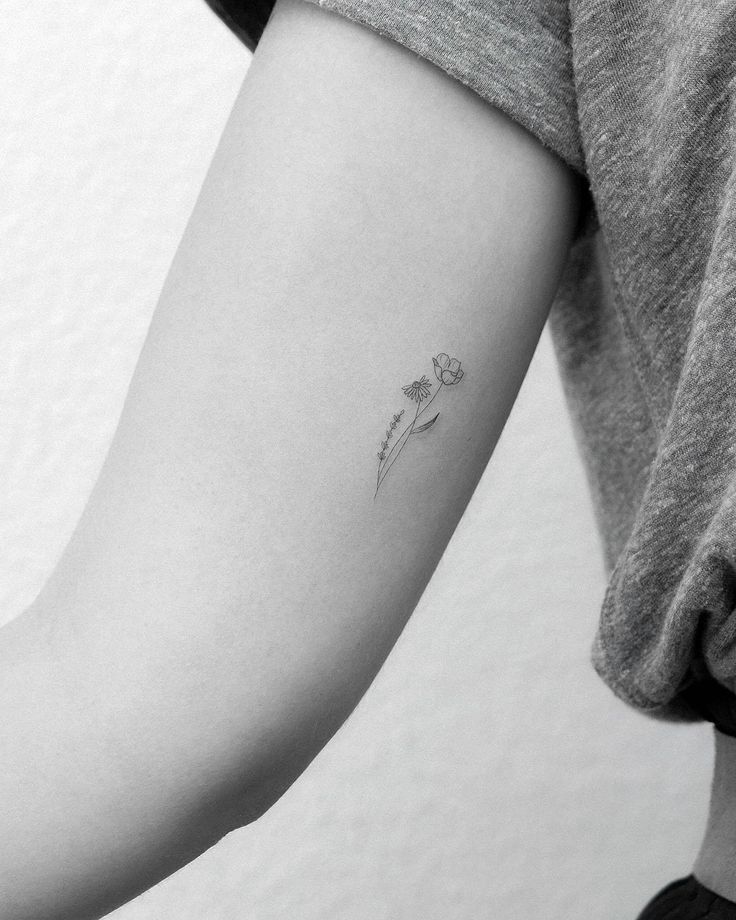 a woman's arm with a single flower tattoo on the left side of her arm