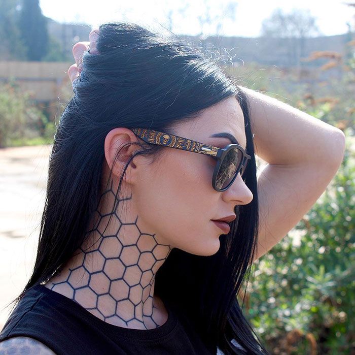 a woman with black hair wearing sunglasses and a neck piece that has honeycombs on it