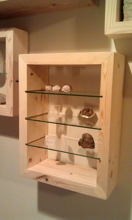 a wooden shelf with glass shelves and rocks in the bottom, along with other items