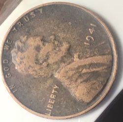 a close up of a coin on a white surface with a black object in the background