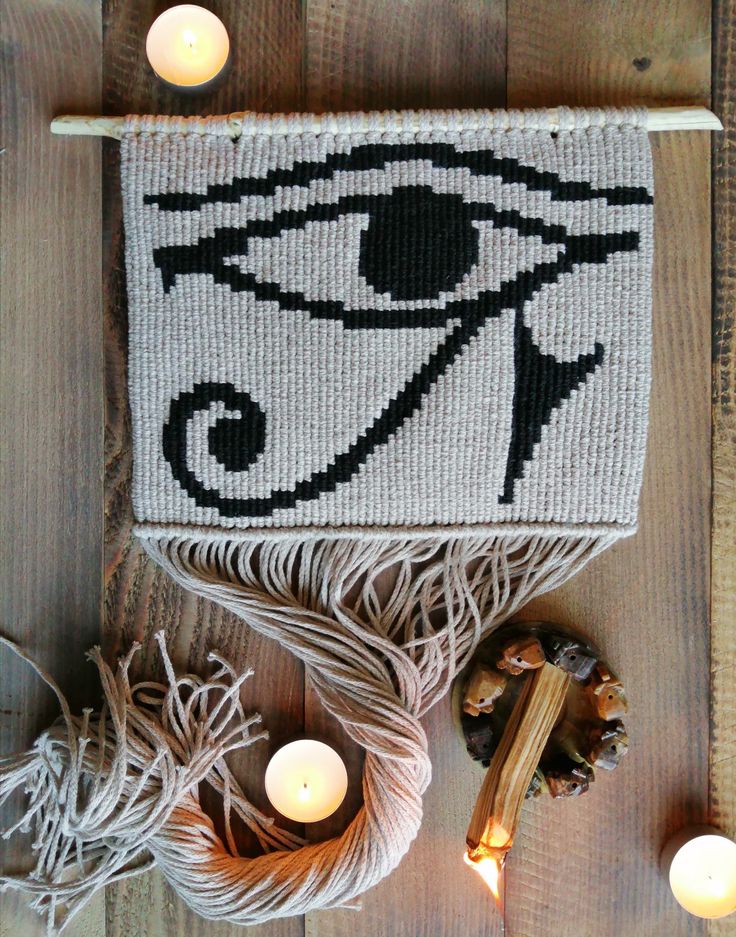 a table topped with candles next to a knitted rug and an eye on it