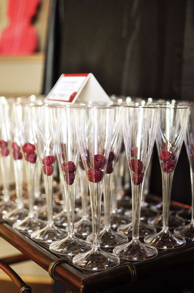 many wine glasses are lined up on a tray with red berries in them and one is empty