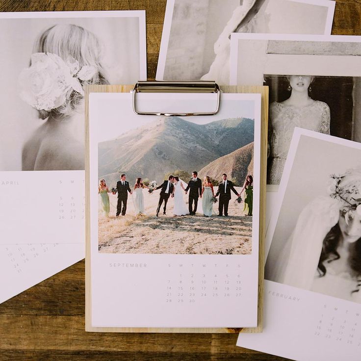 a calendar sitting on top of a wooden table next to pictures and photos pinned to a clipboard