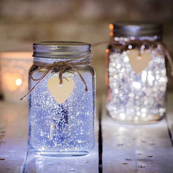 two mason jars with lights in the background and a heart shaped tag attached to them