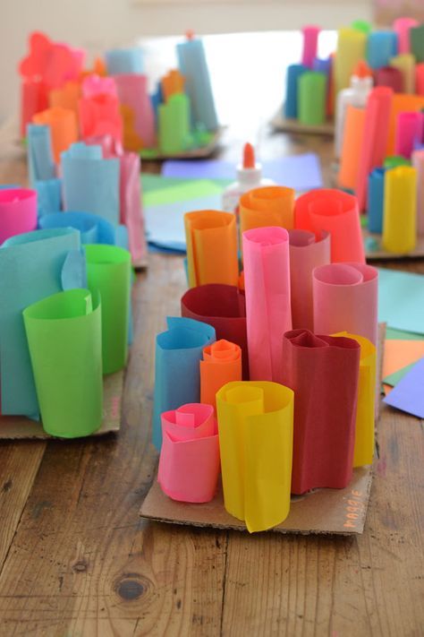 many different colored cups are sitting on a wooden table with papers laid out in front of them