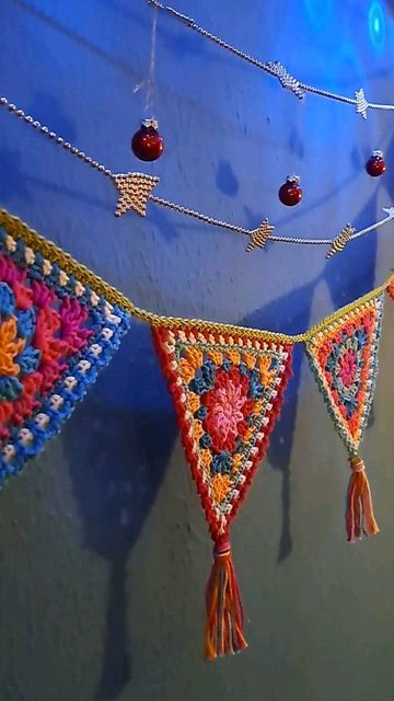 colorful crocheted decorations hanging from a blue wall with beads and tassels