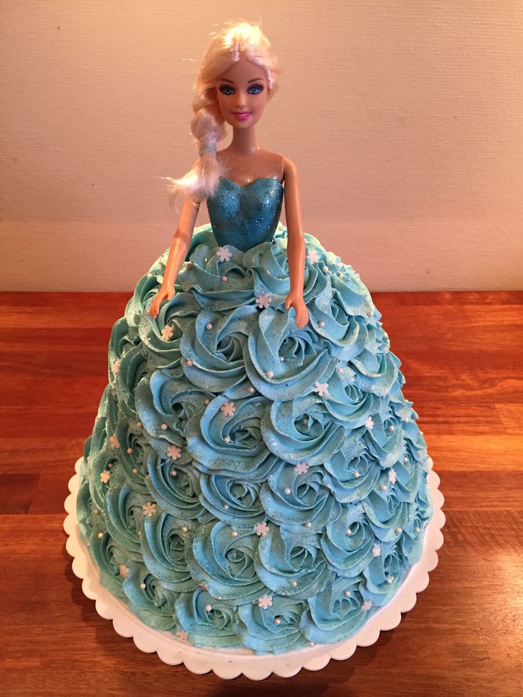 a barbie doll cake with blue frosting and stars on the top, sitting on a wooden table