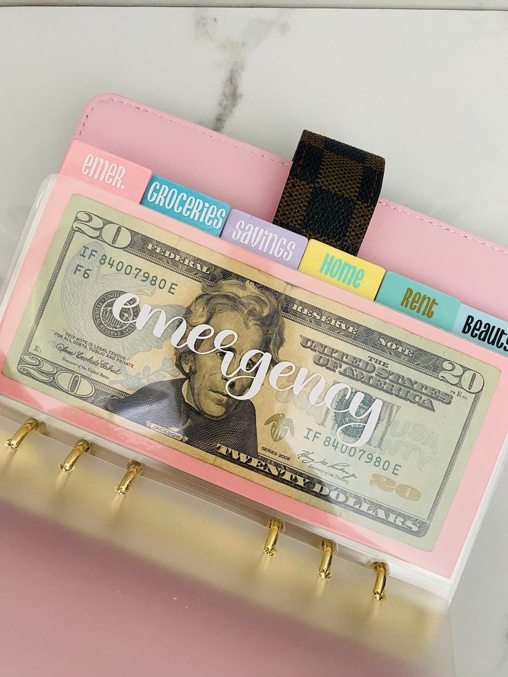 a pink purse with a money clip attached to it and the word emergency written on it