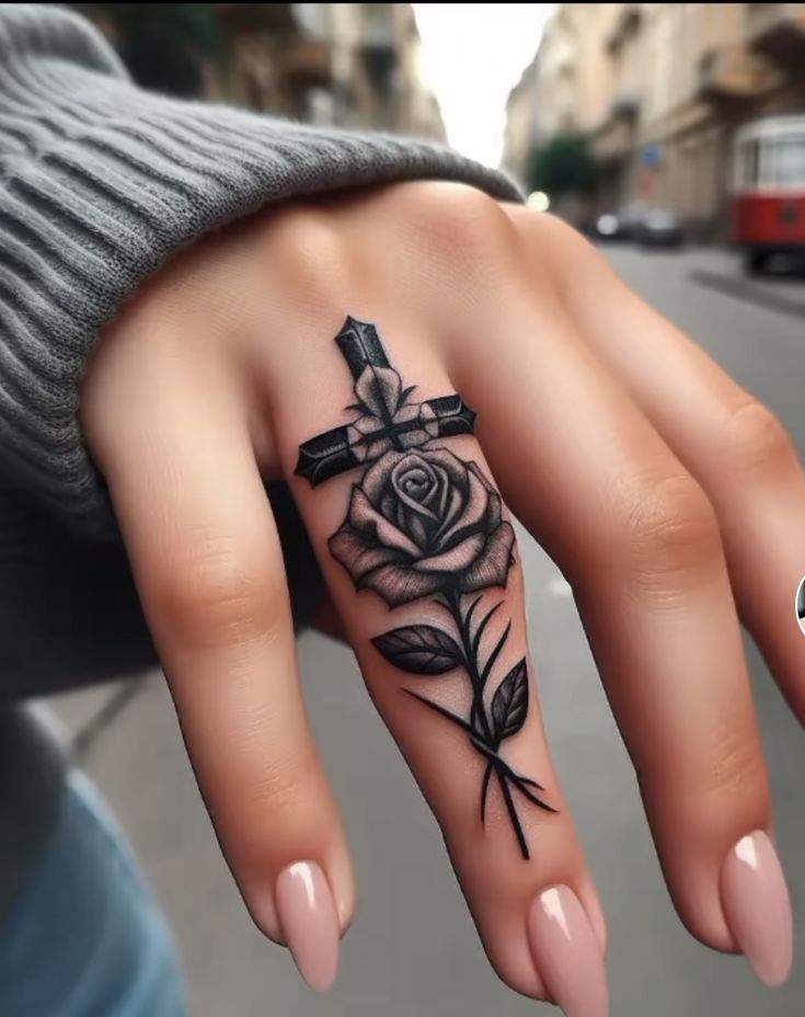 a woman's hand with a cross and rose tattoo on it