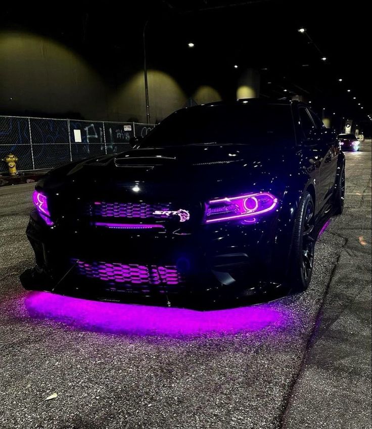 a black car with purple lights on it's hood and the front end of it