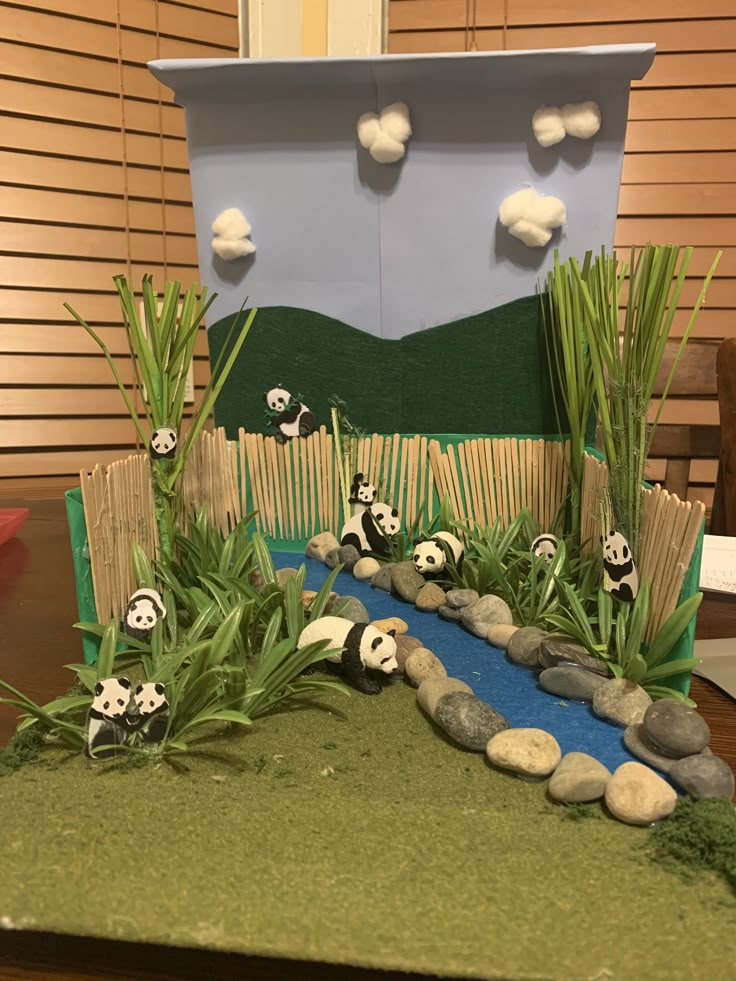 a cake with pandas on it sitting on top of a table next to grass and rocks