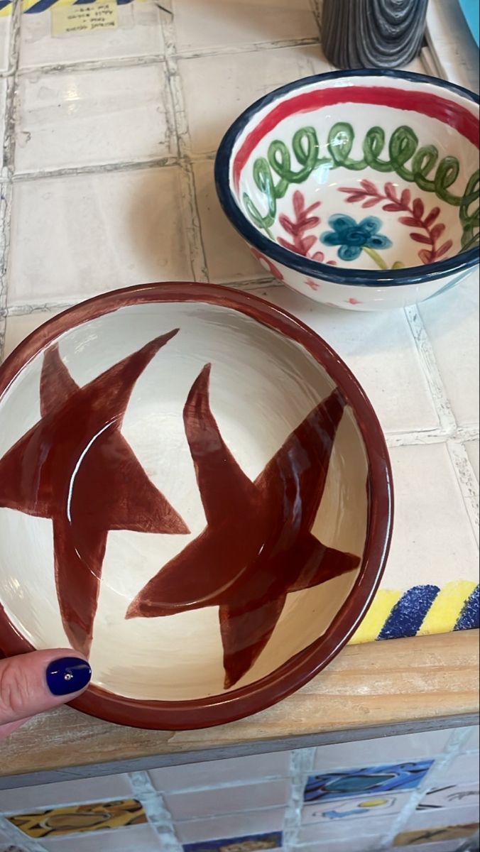 a person is holding a bowl with two fish painted on it