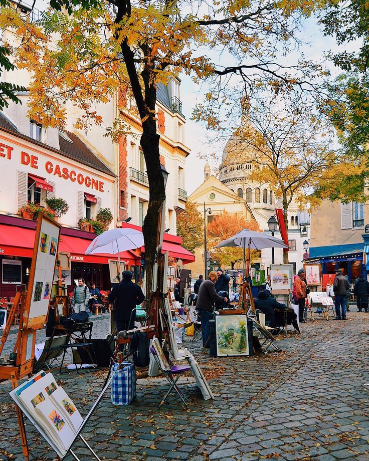 an outdoor art market with people and umbrellas