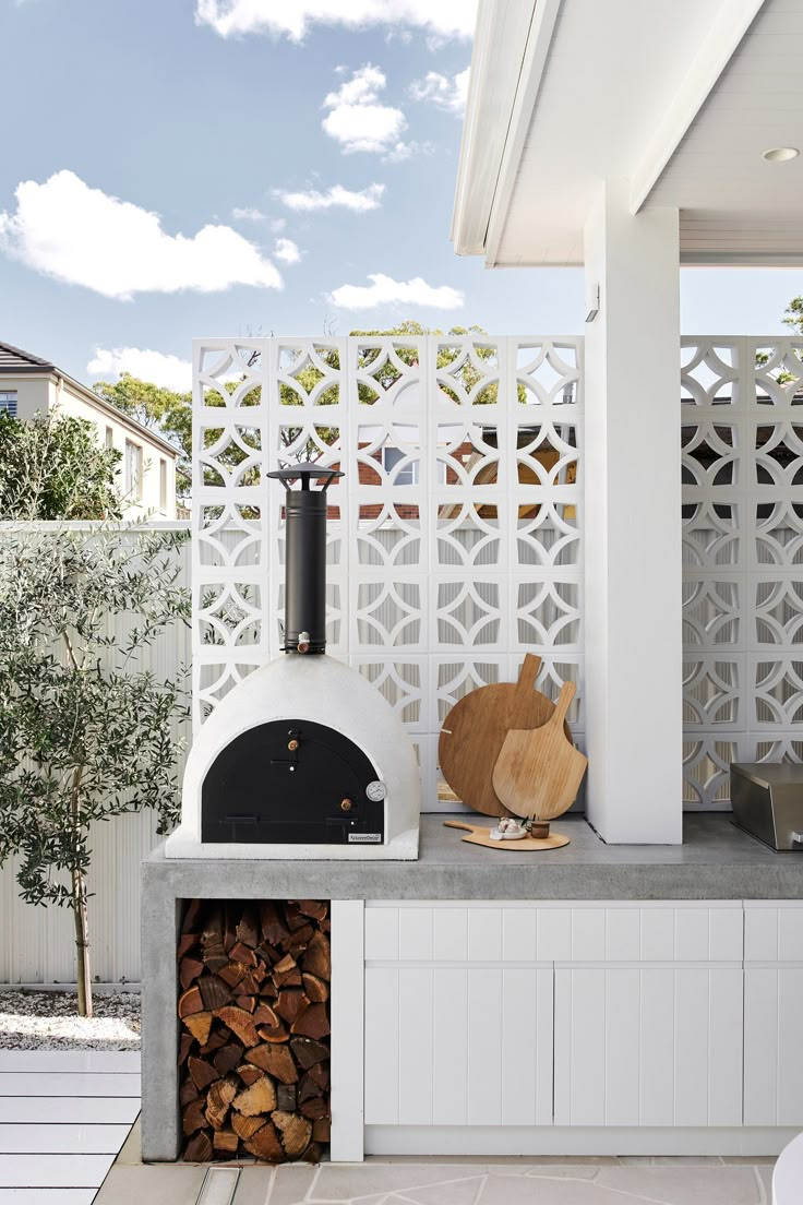 an outdoor pizza oven is built into the side of a white fenced in area