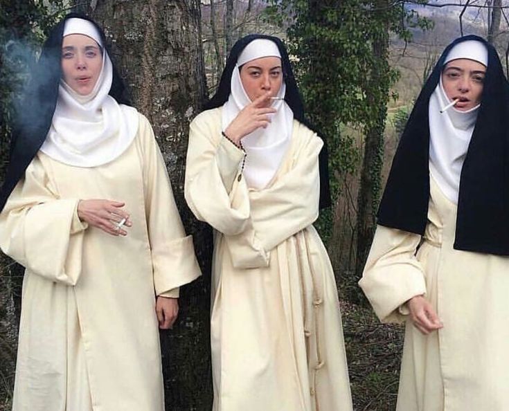 three women dressed in nun costumes standing next to each other with their hands on their mouths