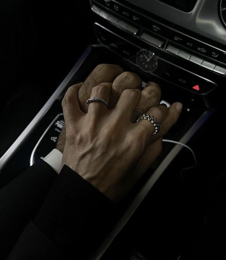 a man in a black suit is holding the steering wheel and pressing buttons on his car