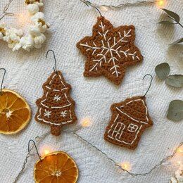 three crocheted ornaments on a table next to some orange slices and popcorn cones