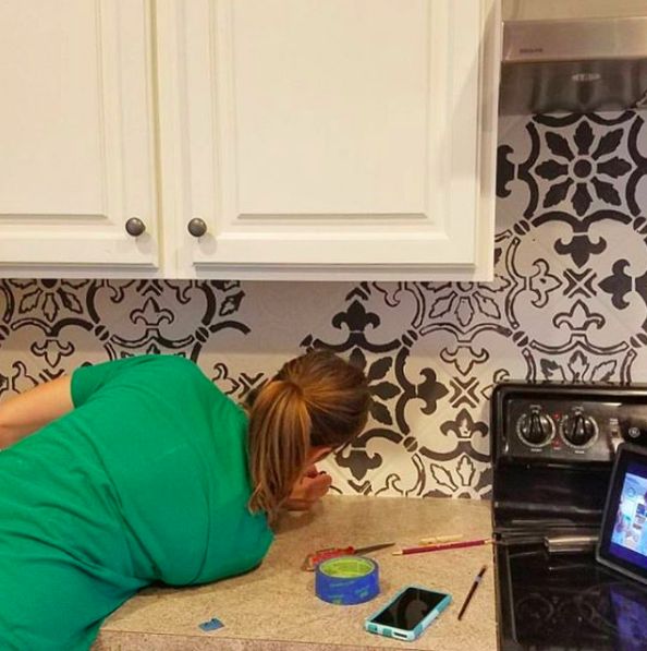 a woman laying on the kitchen counter next to an appliance with a cell phone