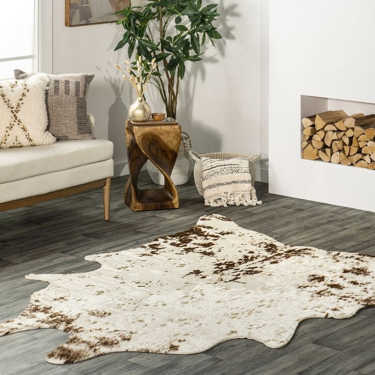 a white and brown rug in a living room with wood logs on the floor next to it