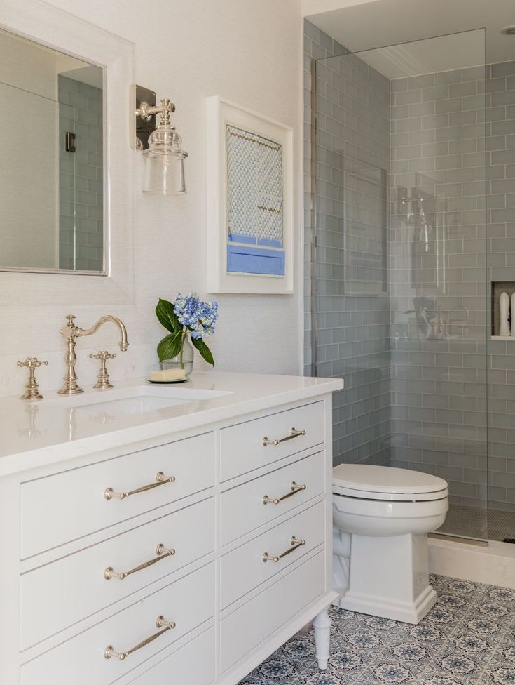 a bathroom with blue and white tile flooring, shower stall and sink area next to the toilet