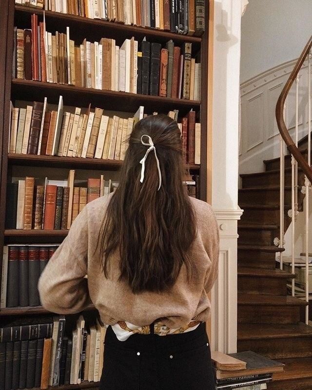 a woman standing in front of a bookshelf