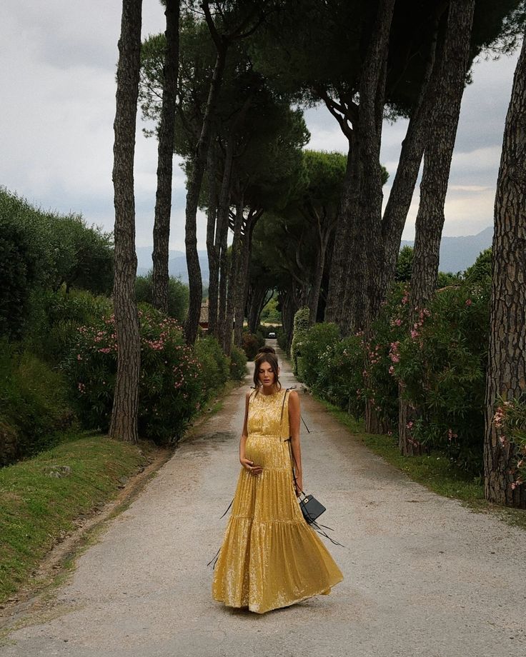 a woman in a yellow dress is walking down the road