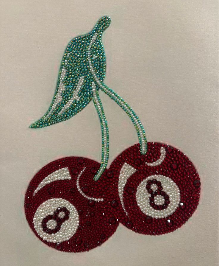 two red balls with numbers on them are hanging from a green beaded string that is attached to a white piece of cloth