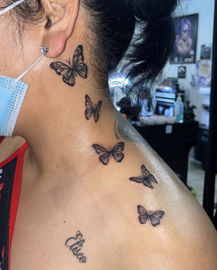 a woman wearing a face mask with butterflies on her neck and behind her ear tattoo