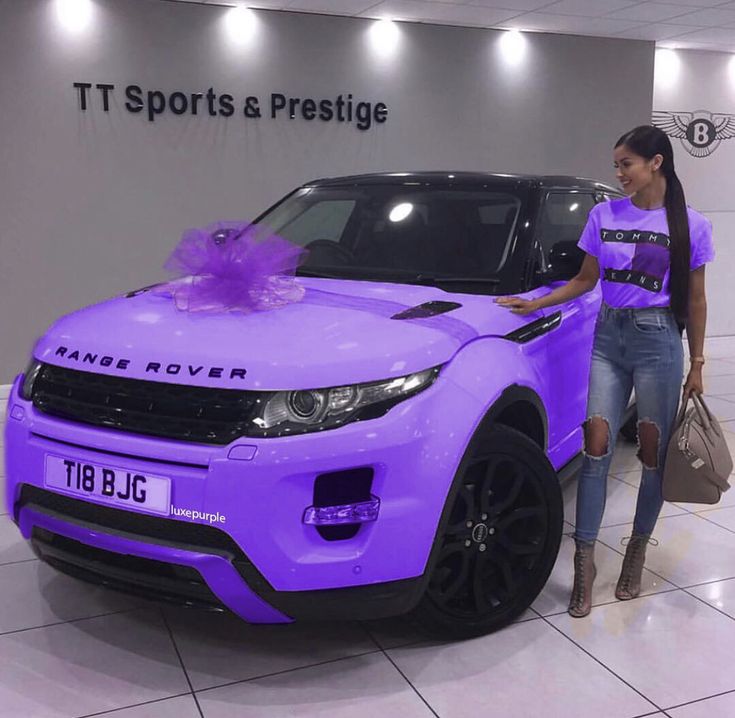 a woman standing next to a purple range rover in front of a sign that says it sports and prestige