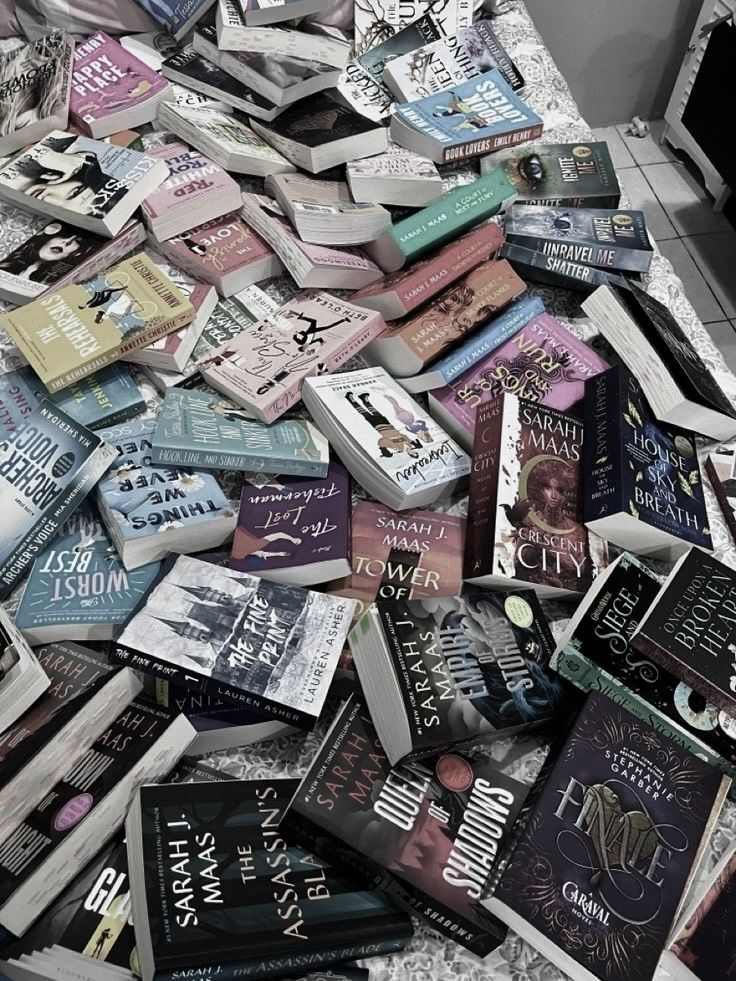 a pile of books sitting on top of a floor next to a sink and mirror