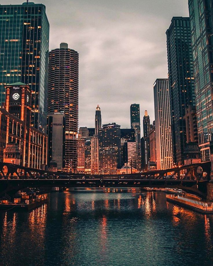 the city skyline is lit up at night with lights reflecting in the water and skyscrapers