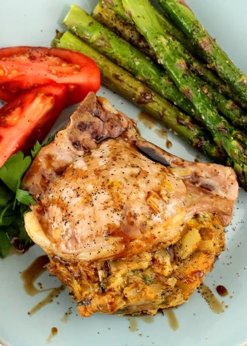 a white plate topped with meat and veggies next to a pile of asparagus